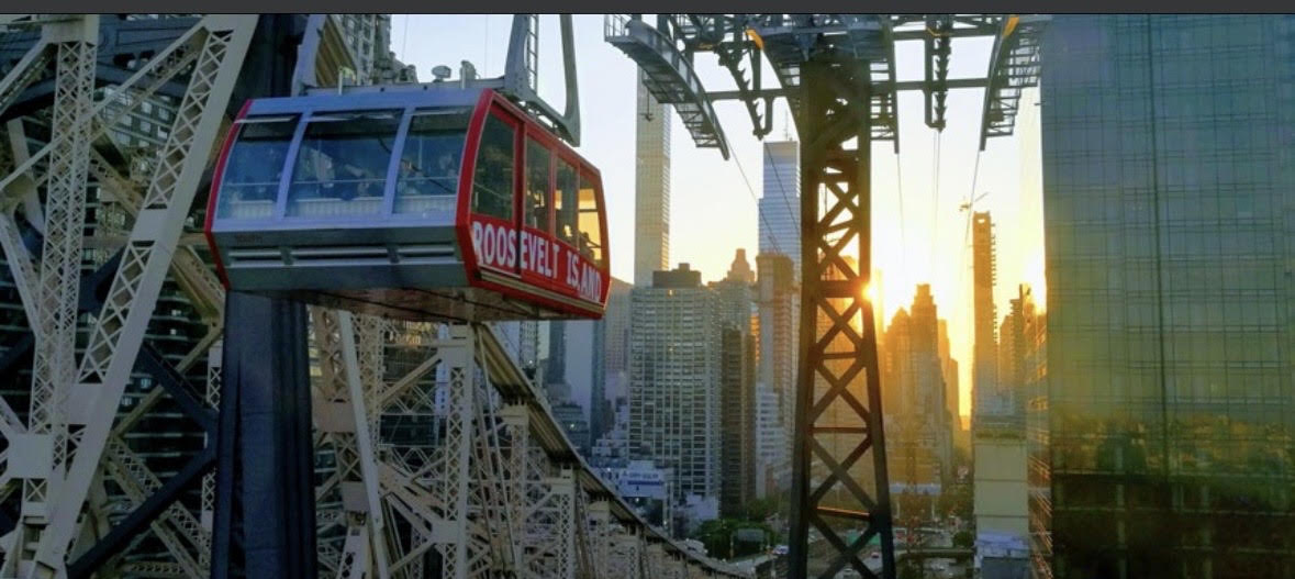 The Roosevelt Island tram car crossing toward the Manhattan skyline at sunset